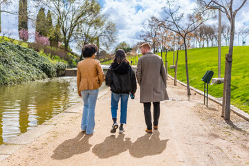 Friends walking along canal in city park during spring