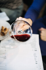Participant swirling red wine over a tasting card during a wine workshop. Wine workshop, sensory...