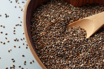 Chia seeds in a heart-shaped wooden bowl with a wooden spoon.