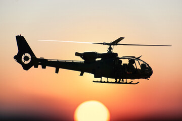 Silhouette of combat helicopter at sunset in the sky, gazelle side view, air transportation © Reflexpixel