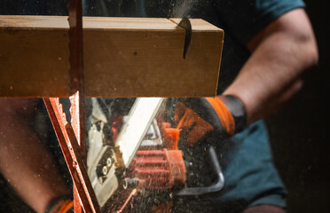 Worker uses a chainsaw to cut a plank into two pieces while working