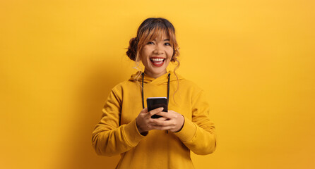 Cheerful young asian woman typing on a smartphone