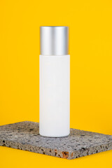 Cosmetic product in tube, bottle, lotion or serum with stylish props on yellow background. 