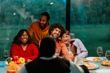 Happy friends having fun during dinner party at home - Cheerful multi-ethnic friends enjoying dinner party at home