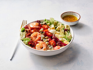 Colorful and appetizing seafood salad features plump shrimp, cherry tomatoes, crisp lettuce, and creamy avocado. A drizzle of zesty dressing completes this delightful dish