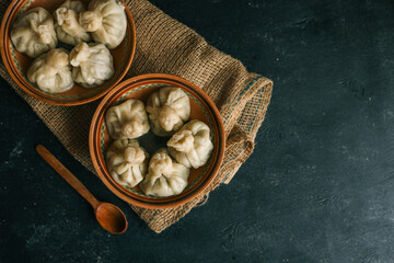Two clay bowls filled with traditional dumplings placed on a rustic burlap cloth over a dark...