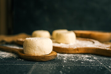 Raw dough rounds on a floured wooden board with a heart shape drawn in flour, flat lay of homemade baking preparation