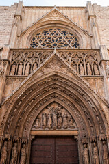 Gothic cathedral entrance with stone sculptures and stained glass rose window captured in vertical perspective for architectural history and culture visuals