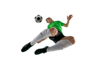 Low angle of strong young man, dressed sport black-green uniform, soccer player leaping for kick against white studio background. Concept of professional sport, training, tournament, energy. Ad
