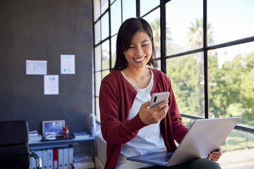 Happy asian woman using phone in office
