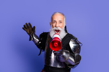 Medieval-styled mature man with white beard holding megaphone in purple setting