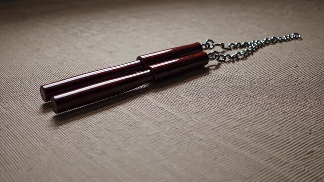Wooden nunchaku weapon placed on textured fabric surface