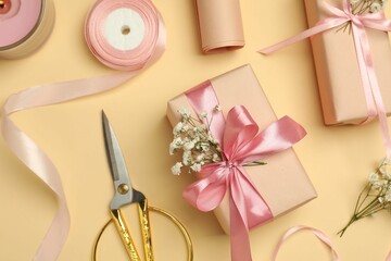 Florist. Boxes, flowers, ribbon, burning candle and scissors on beige background, flat lay