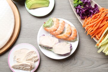 Spring rolls. Rice paper sheets with different ingredients on grey wooden table, flat lay