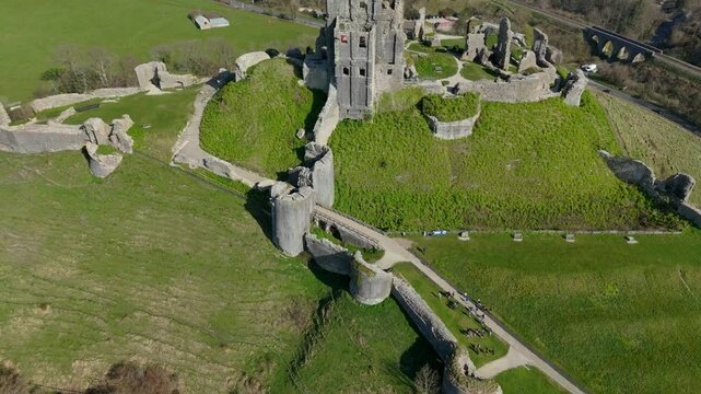 The ruins of Corfe Castle on a green hill in the Purbeck Hills, England on a sunny bright day