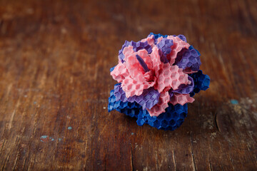 pink purple and blue textured candle in shape of a flower made from natural bee wax on old rustic...