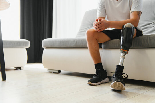 A young man puts on a prosthetic leg at home. Amputation and use of an artificial leg - Powered by Adobe