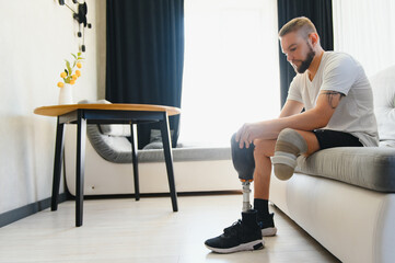 Thoughtful young pensive man amputee with prosthetic leg disability above knee transfemoral leg...