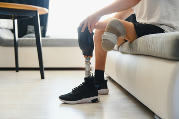 A young man puts on a prosthetic leg at home. Amputation and use of an artificial leg