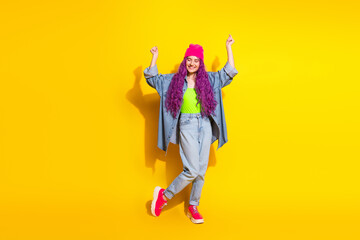 Stylish young woman in casual attire posing with vibrant purple hair and a cheerful attitude...