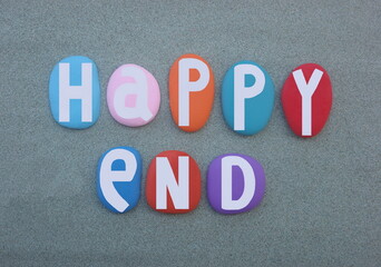 Happy end, creative logo design composed with multi colored hand painted stone letters over green sand