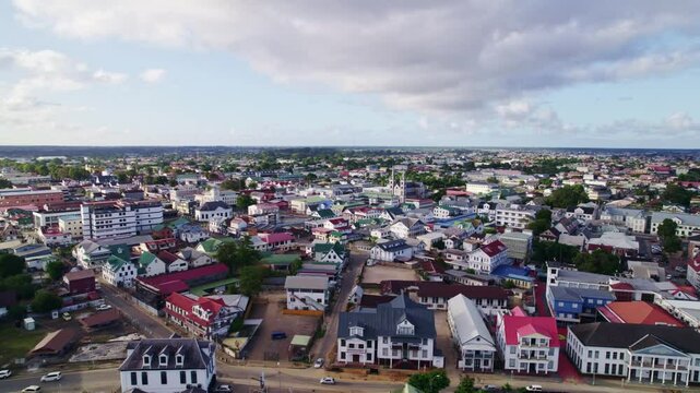 Drone flying over buildings in heritage City of Paramaribo, Suriname river side, aerial sunset
