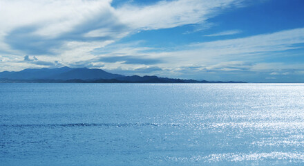 Obraz premium 青い空と輝く海 青空に浮かぶ夏の積雲 風に流れる雲の風景 キラキラ輝く波の背景 夏休み・アウトドア・観光・旅行・行楽・バカンスのイメージ