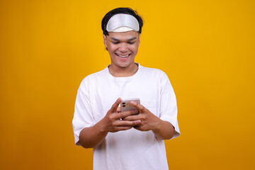 Young Calm Man in White Pajamas and Eye Mask Using Smartphone in Hand