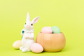 Easter bunny with painted eggs on color background