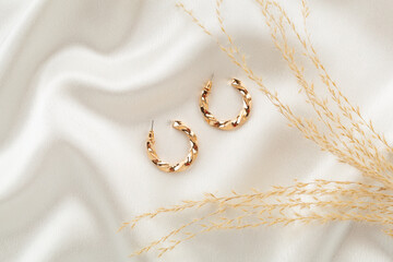 Elegant golden jewelry with decoration on textile background, top view