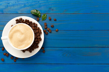 Cup of coffee with coffee beans and leaves on wooden background,top view