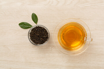 Cup of tea with dry and fresh leaves on wooden background, top view
