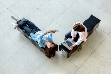 Female students sitting on benches and studying together in the university lobby