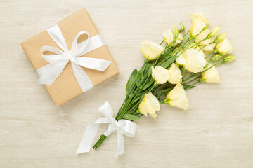 Gift box with beautiful bouquet on wooden background, top view