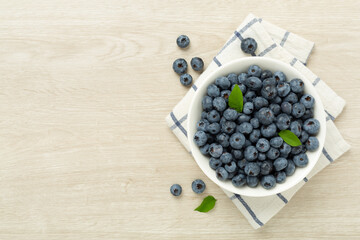 Bowl with fresh bright blueberries on wooden background,top view