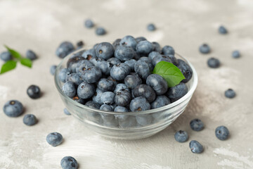 Bowl with fresh blueberries on concrete background