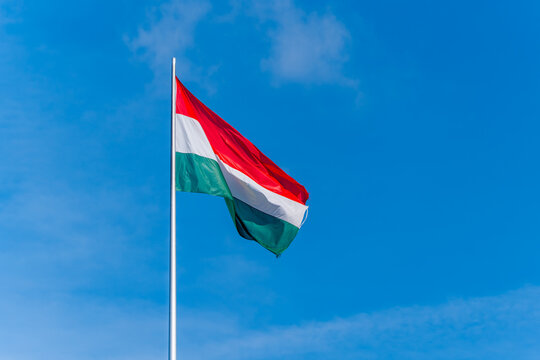 The flag of Hungary flutters in the sky. Flag on a pole.