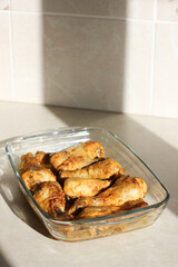vertical close up of home style crispy roasted chicken legs drumsticks in garlic mayo sauce in a transparent glass cooking dish in kitchen with sunny light background