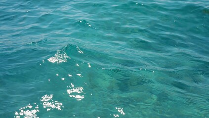 Fototapeta premium Clear turquoise sea water with sunlight reflecting on the surface creating a peaceful and vibrant natural background perfect for tropical themes, ocean textures, marine concepts, aqua summer bright.