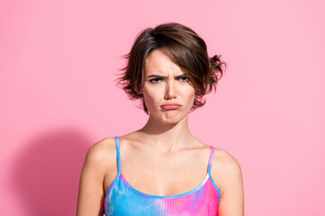 Charming young woman in a vibrant summer dress expressing surprise against a pink background