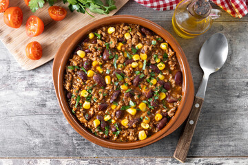 Traditional Mexican Chili con carne. Minced meat and vegetables stew in tomato sauce on wooden table