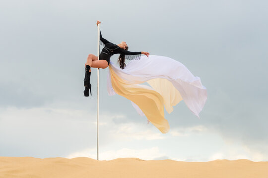 Athletic Dancer with Flowing Fabric on Pole in Sandy Landscape — Dramatic Sky Background with Copy Space