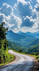 Fototapeta premium Serene Mountain Road Winding Through Lush Greenery Under a Cloudy Blue Sky Offering a Picturesque View and Tranquil Atmosphere for Travel Adventure