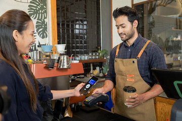 Man owner coffee shop submit an electronic cash register and coffee cup to woman customer, Female...