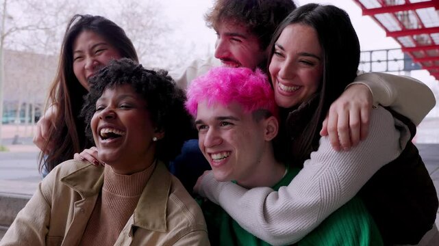 Diverse young happy people having fun together outdoor. Youth community concept with multiracial friends laughing and hugging each other over urban background. Friendship and diversity concept.