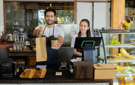 Multicultural couple startup small business bakery cafe restaurant coffee shop wearing apron uniform together partnership, Indian male Asian female barista happy working opening food store teamwork - Powered by Adobe