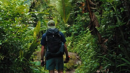 Young man enjoying tropical waterfall view at Sekumpul waterfall in Bali island, Indonesia.
