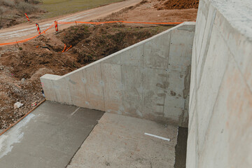 Concrete wall rising on construction site near dirt road