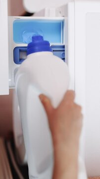 Vertical Format Video of Woman pouring gel detergent in washing machine. Putting Laundry Detergent Pod into the Washing Machine. Washing clothing in domestic washing machine