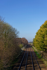 Fototapeta premium The East Coast Main Rail Line passing by Barry Links Station between the farm fields of this rural coastal location on a sunny day in April.
